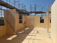 Stavba šestipodlažní budovy z CLT v Modeně, Itálie, s viditelnými dřevěnými panely a konstrukcí při montáži.