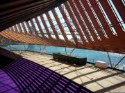 Detailní pohled na architektonickou konstrukci pod ikonickými plachtami opery v Sydney.