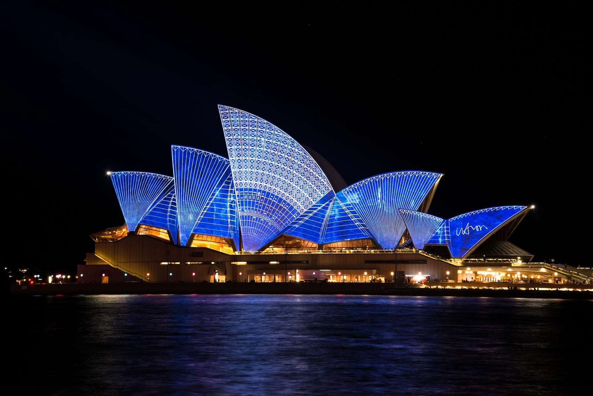 Osvětlení architektonické struktury opery v Sydney v noci.