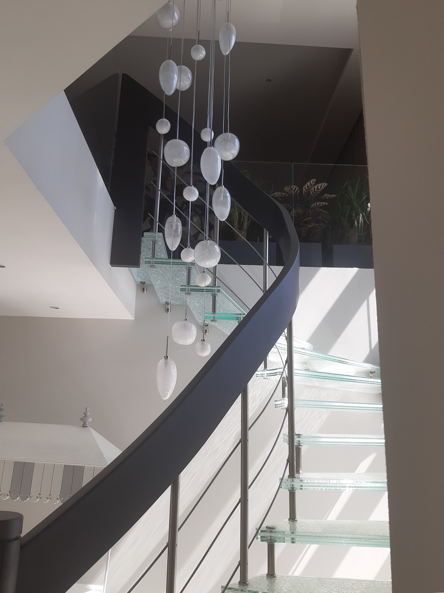 Gebogene Treppenwange aus Brettschichtholz, die zur Treppe aus verschiedenen Materialien gehört (Holz, Stahl, Glas) Antibes, Frankreich (© YLEx)