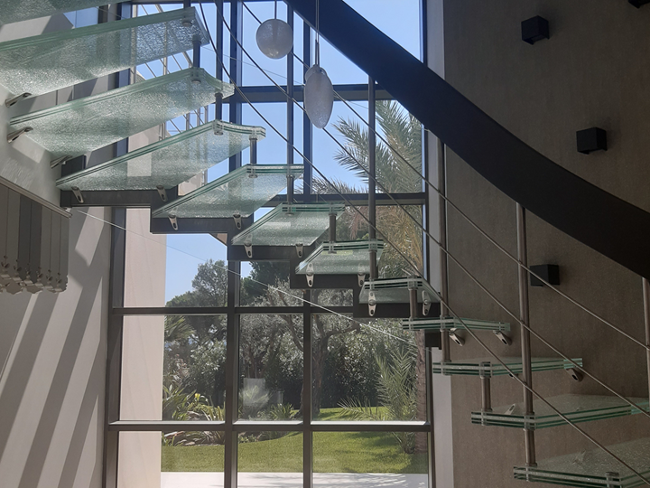 Gebogene Treppenwange aus Brettschichtholz, die zur Treppe aus verschiedenen Materialien gehört (Holz, Stahl, Glas) Antibes, Frankreich (© YLEx)