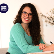 Katie, die neue Kollegin, lächelt in die Kamera und trägt eine Bürokleidung.