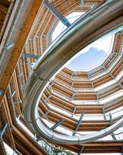 Innenansicht eines Aussichtsturms mit integrierter Tunnelrutsche, moderne Architektur.