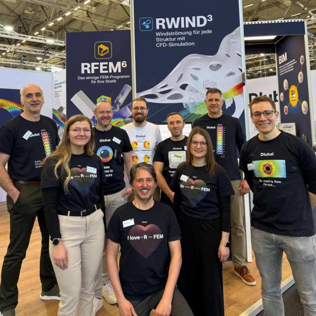 Eine Gruppe von Ingenieuren, die ein Tragwerksmodellprojekt besprechen, in professioneller Kleidung und in einer technischen Büroumgebung stehend.