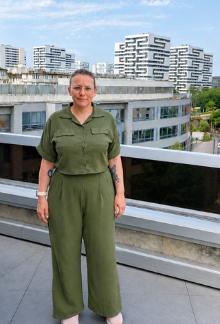 Neuer Kollege von Dlubal Software France steht auf einer Büroterrasse mit modernen Stadtgebäuden im Hintergrund.