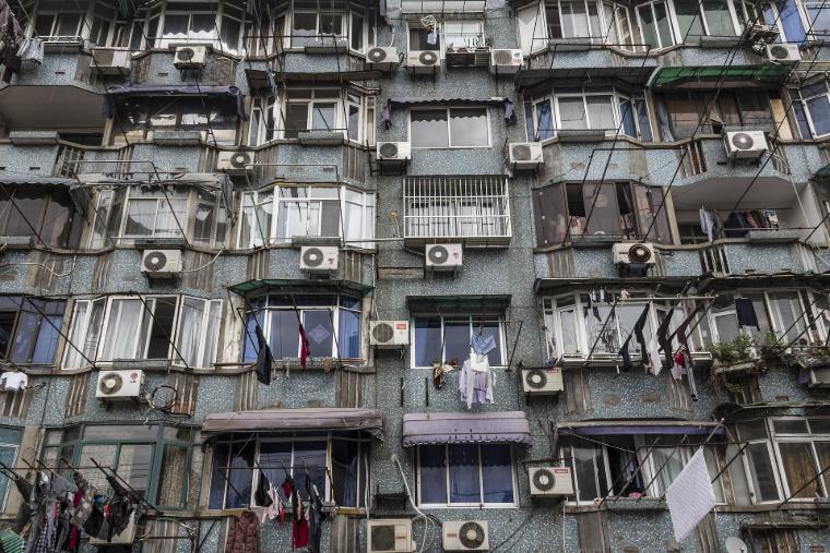 Fassade eines Wohnhauses mit zahlreichen Klimaanlagen, die zur städtischen Überhitzung beitragen, da die Abwärme durch engstehende Gebäude nicht entweichen kann.
