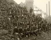 Miners gather in front of a conveyor station, a classic image of industrialization in mining.