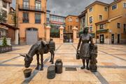 Sculpture of the milk woman in Plaza Trascorrales in Oviedo, surrounded by typical buildings.