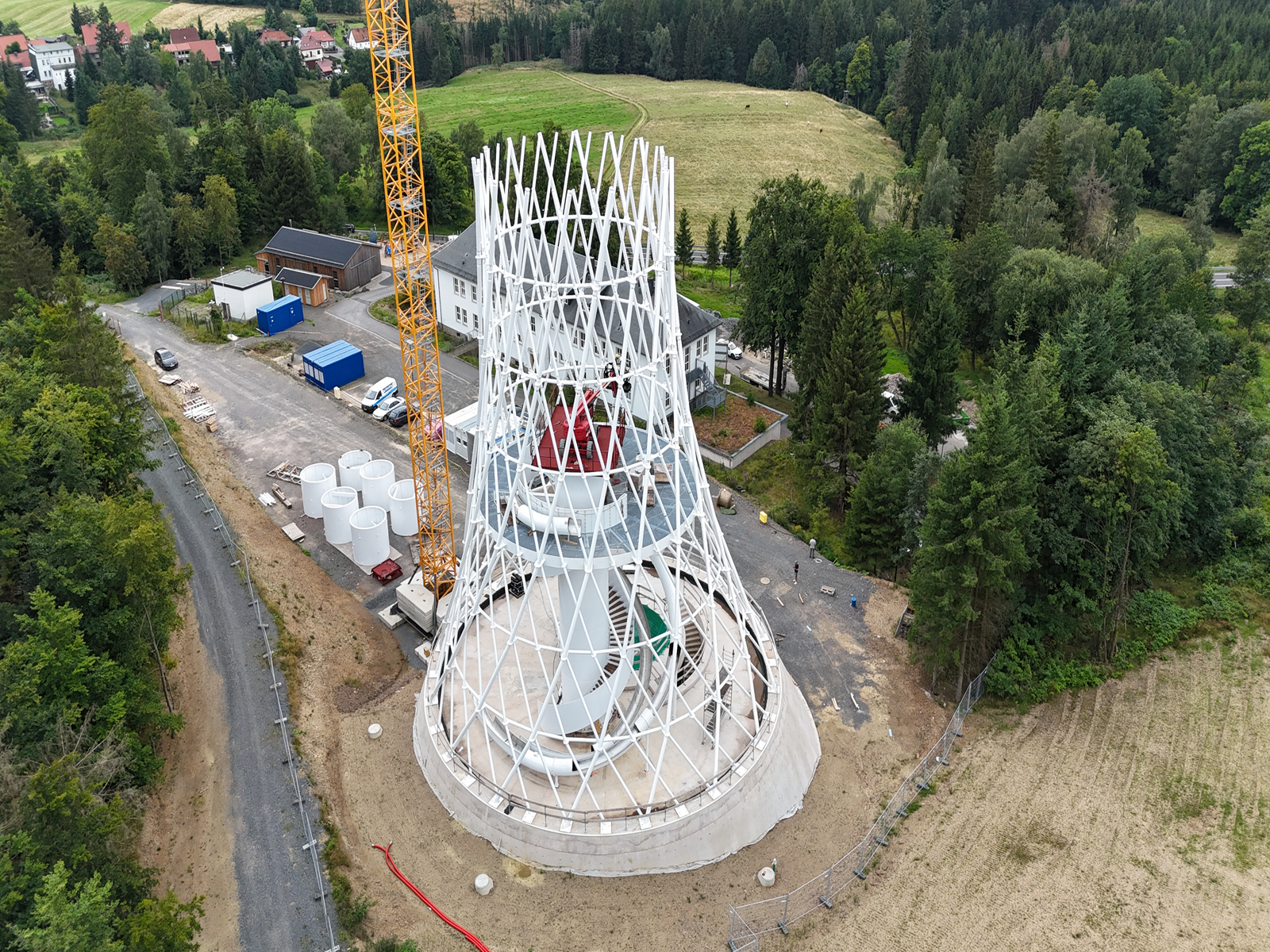 Construction process of the Hexenbesen Tower by ibr tragwerk Barth + Rugenstein with scaffolding and building materials in the foreground.