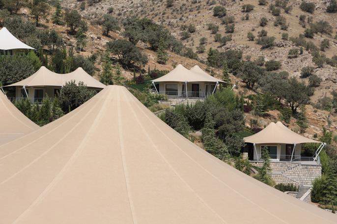 Membrane roof in mountainous terrain; modern architecture harmonizes with natural surroundings.