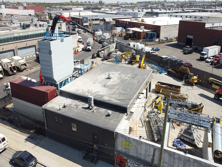Aerial view of a concrete mixing plant during installation, surrounded by construction activity.