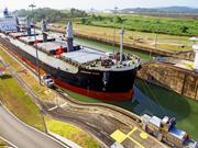 A container ship is sailing through the Panama Canal in daylight.