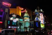 Large billboards and signs on the Las Vegas Strip at night, brightly lit.