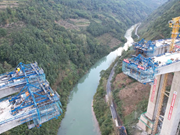 Puente en construcción sobre el río Mabian con carros de avance y cestas colgantes