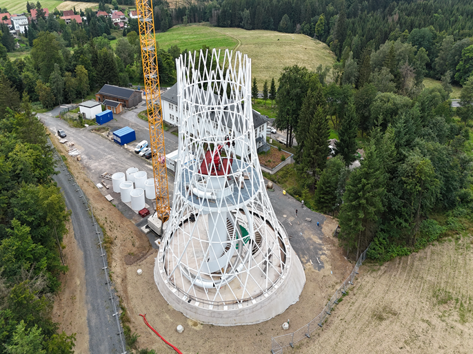 Construcción de la torre Hexenbesen por ibr tragwerk Barth + Rugenstein con andamios y materiales de construcción en primer plano.