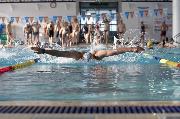 Nadador en una piscina compitiendo por llegar el primero a la línea de meta
