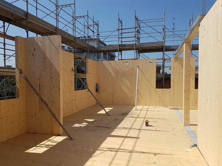 Obra de un edificio de CLT de seis plantas en Modena, Italia, con paneles y estructura de madera visibles durante el montaje.