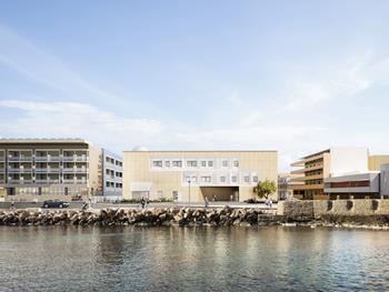 Le projet intègre de la pierre locale, des accès en terrasses et des évasements dynamiques pour créer des espaces éducatifs et communautaires flexibles.