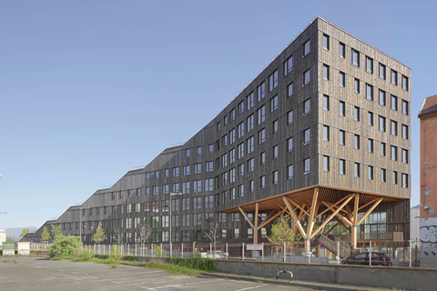 Immeuble de bureaux de six étages avec parking situé au centre de Grenoble, France, illustrant une infrastructure urbaine moderne.