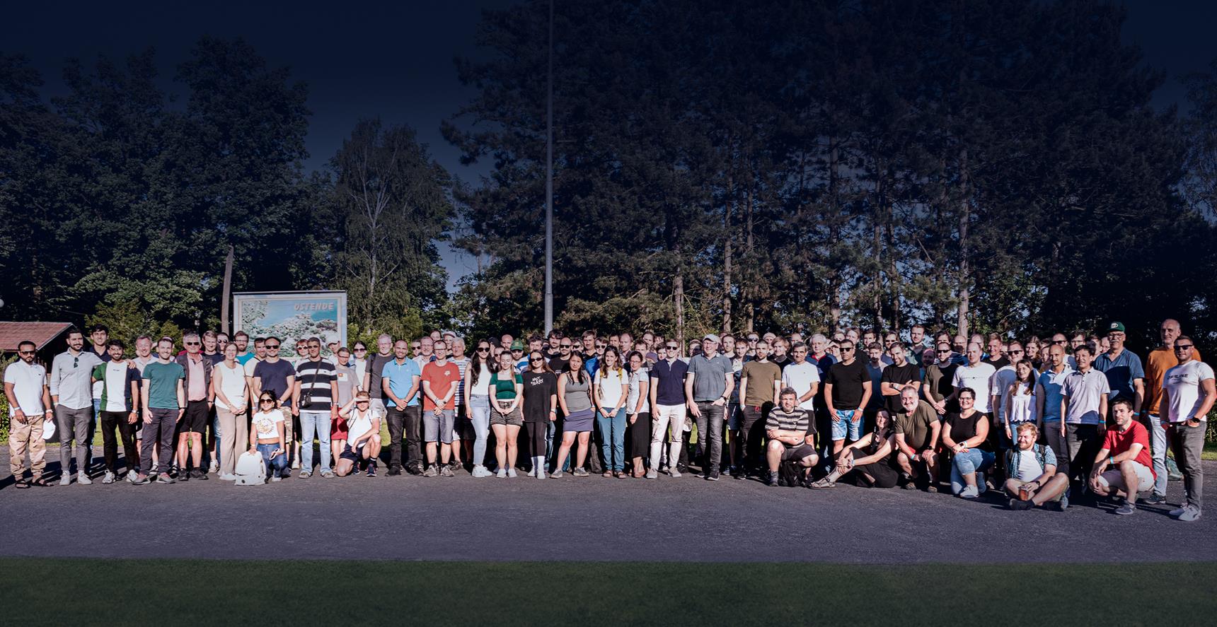 Un groupe de collègues réunis en plein air pour un événement de team building, montrant l'unité et la collaboration sous un ciel ensoleillé.