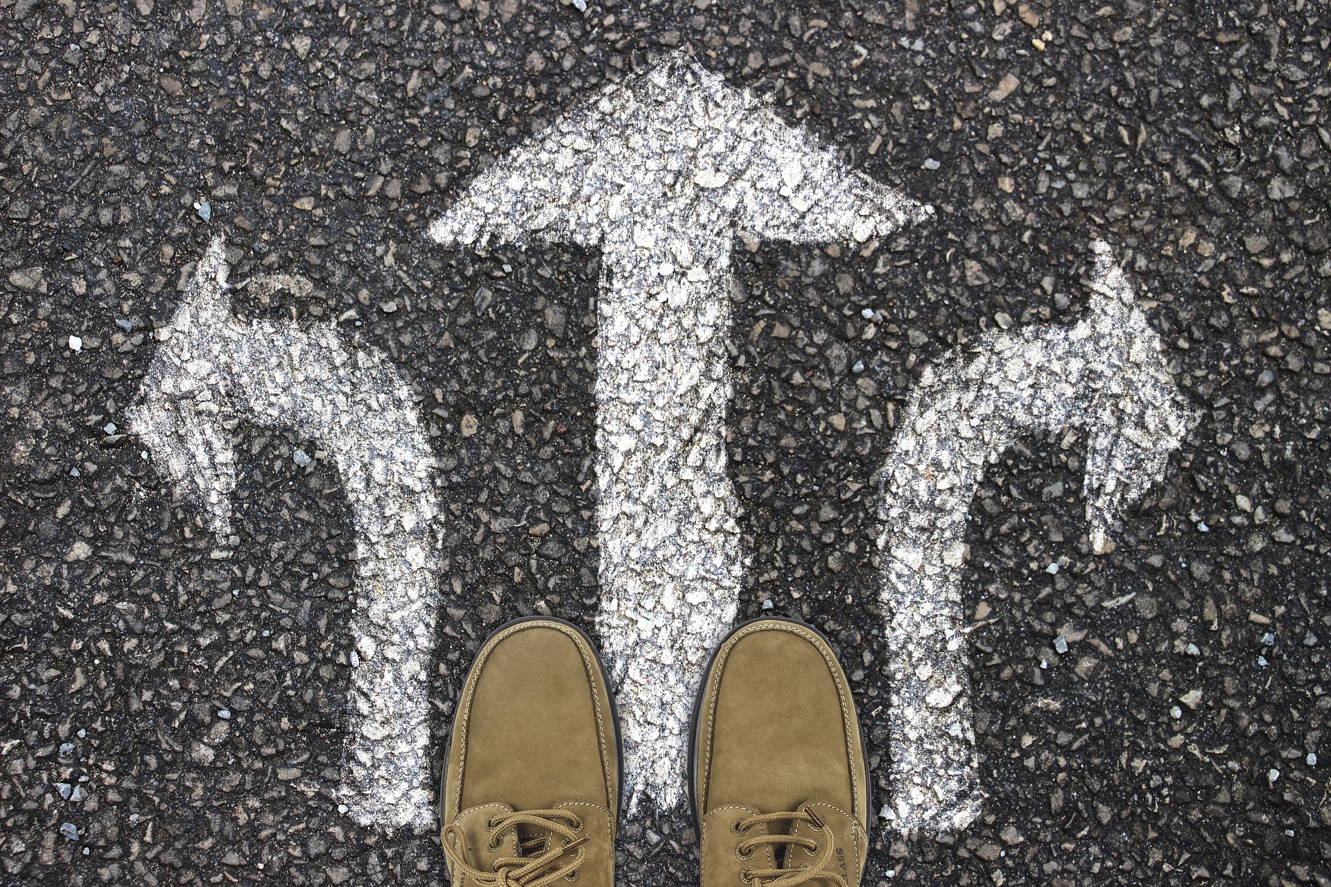Perspective de chaussures sur un sol asphalté avec trois panneaux indicateurs, symbolisant la prise de décision dans la phase de planification.