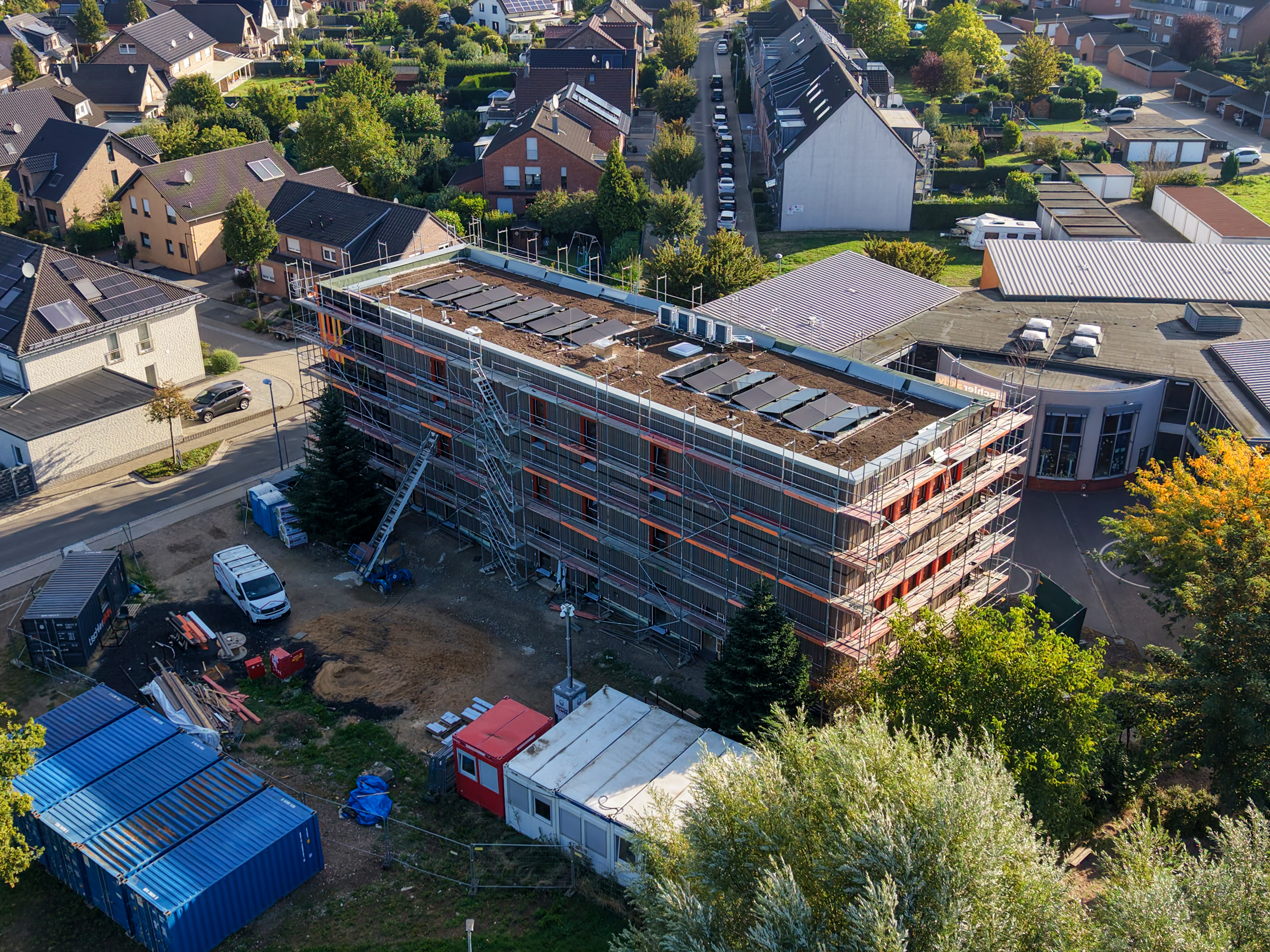 Vue aérienne de l’extension en construction de l’école d’Otzenrath, échafaudages, toiture végétalisée avec panneaux photovoltaïques, chantier urbain.
