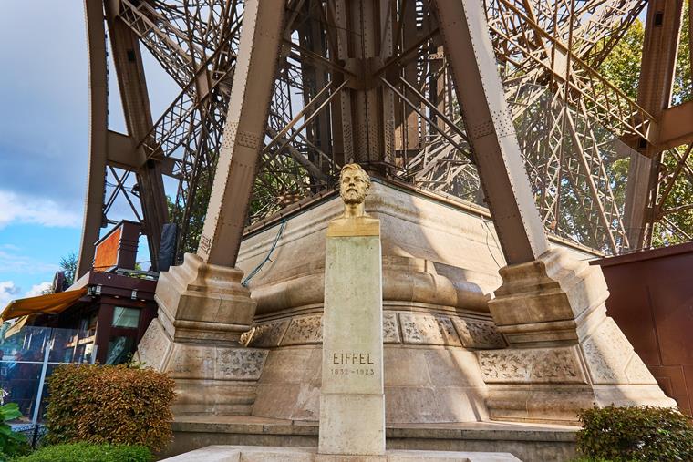 Busto di Gustave Eiffel davanti all'iconica Torre Eiffel a Parigi, Francia.
