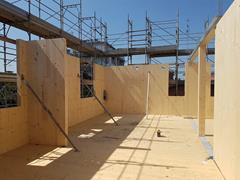 Cantiere di un edificio in XLAM di sei piani a Modena, Italia, con pannelli di legno a vista e struttura durante il montaggio.