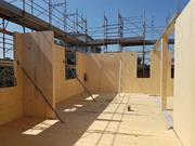 Cantiere di un edificio in XLAM di sei piani a Modena, Italia, con pannelli di legno a vista e struttura durante il montaggio.