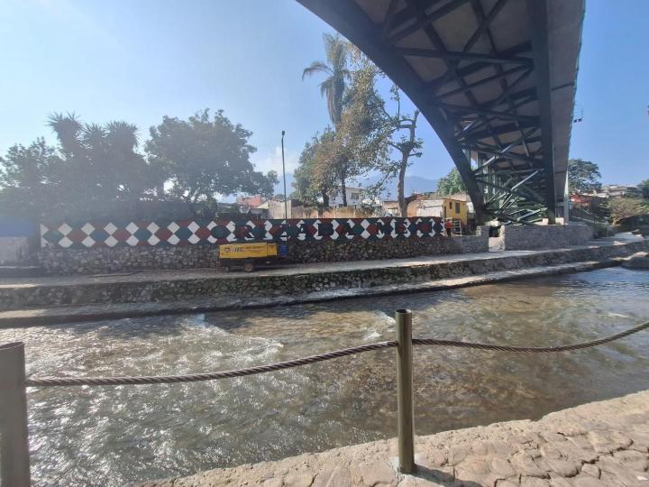 Vista inferiore di un ponte ad arco in acciaio che attraversa il fiume Orizaba a Veracruz, con muro decorato e corso d'acqua