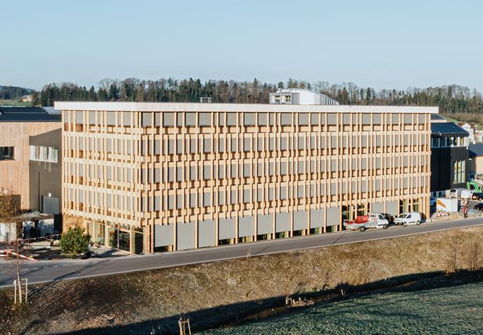 Nowoczesna architektura biurowa w konstrukcji drewnianej z dużą elewacją okienną, zaprojektowana przez Blumer Lehmann