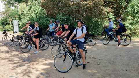 Grupa pracowników jeździ rowerami w ramach inicjatywy wellness, promującej zdrowie i pracę zespołową.