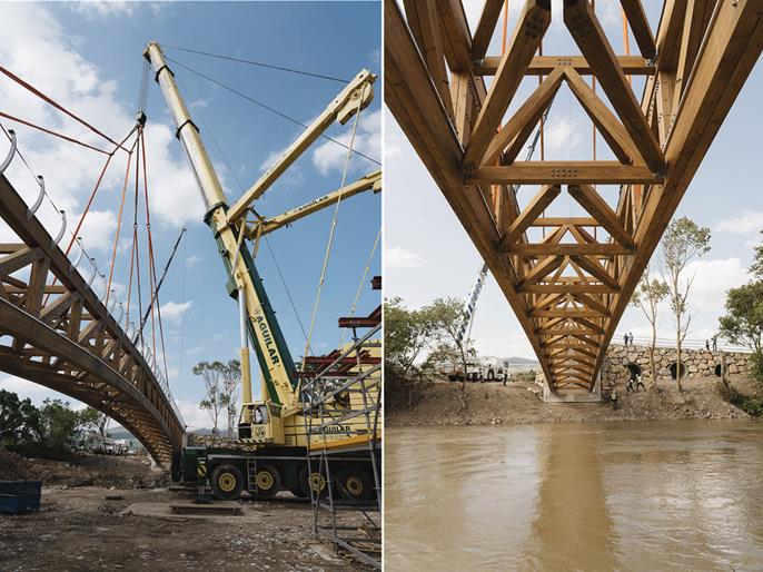 Trabalhadores a terminar a instalação de uma ponte pedonal de madeira.