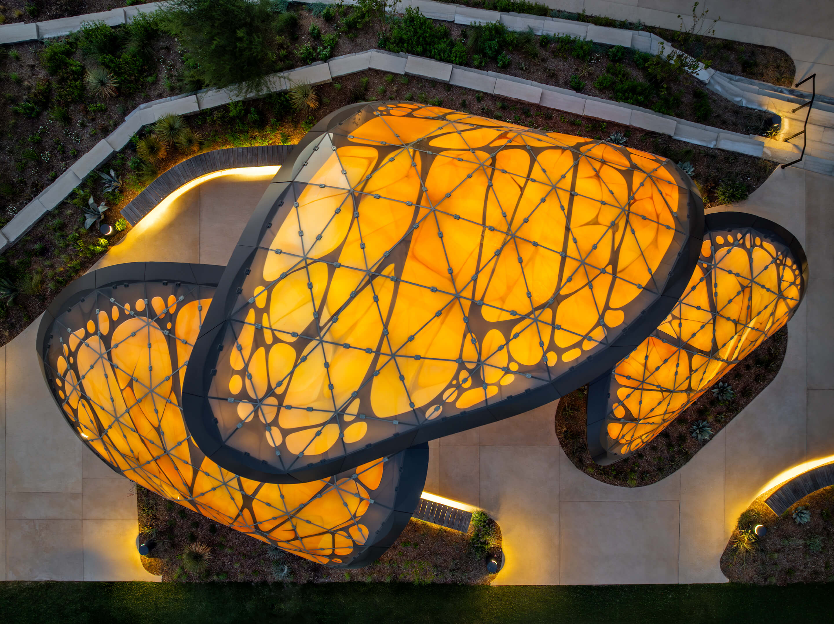 Vista aérea da cobertura em aço de forma orgânica "The Monarch San Antonio" no Texas, EUA, com estrutura de cobertura iluminada.